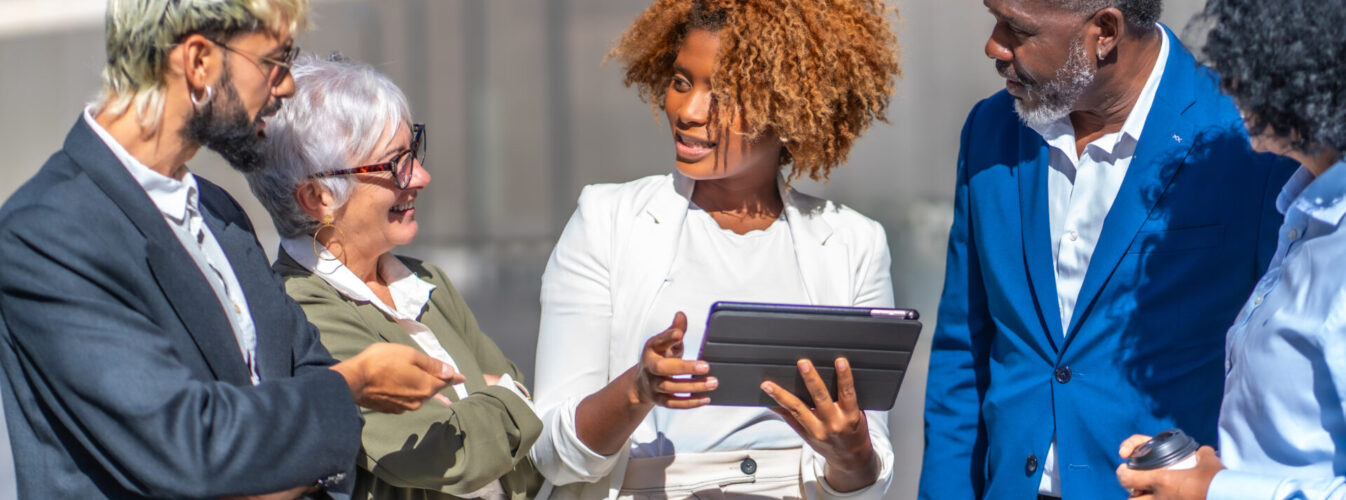 African businesswoman using tablet while explaining a project to colleagues African businesswoman using tablet while explaining a project to colleagues in an outdoors business meeting
